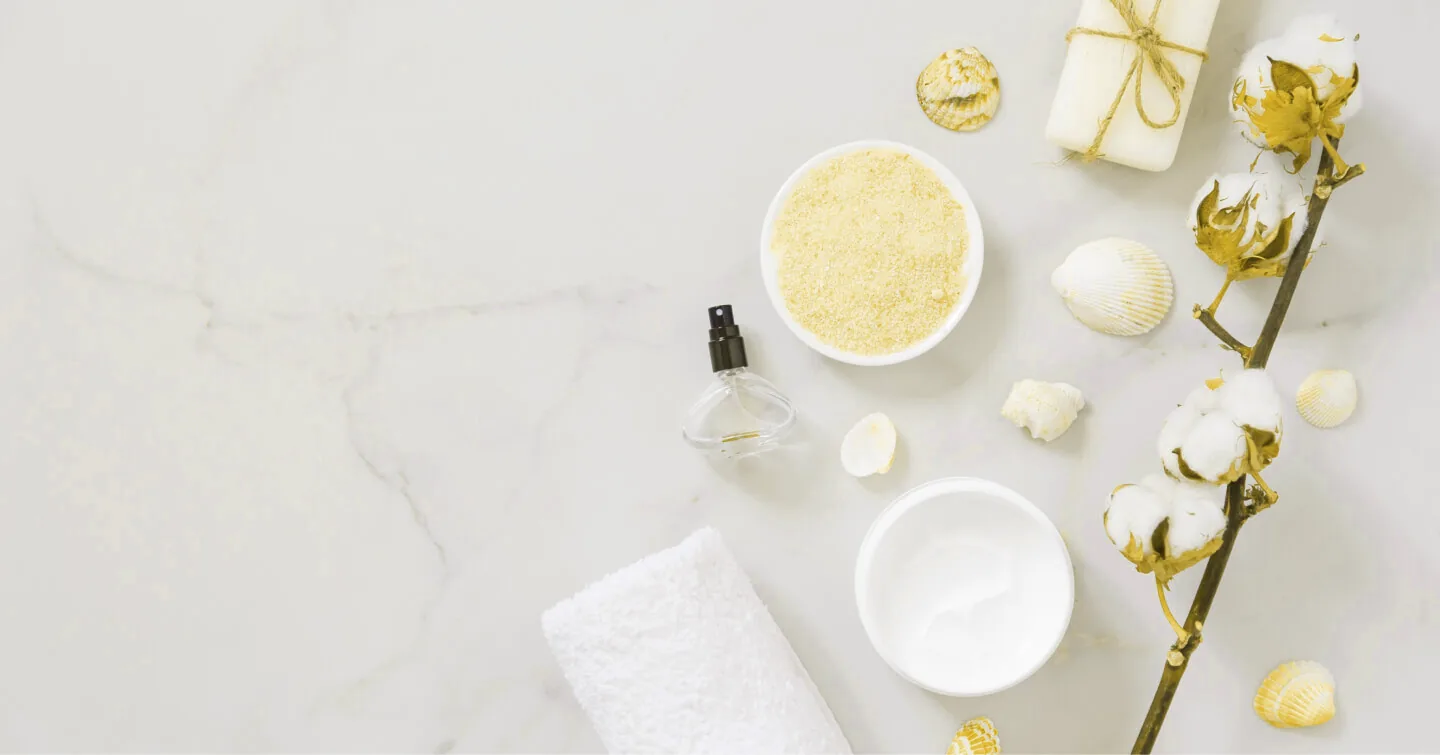 Handdoek, scrub en een vergulde katoentak op wit marmer